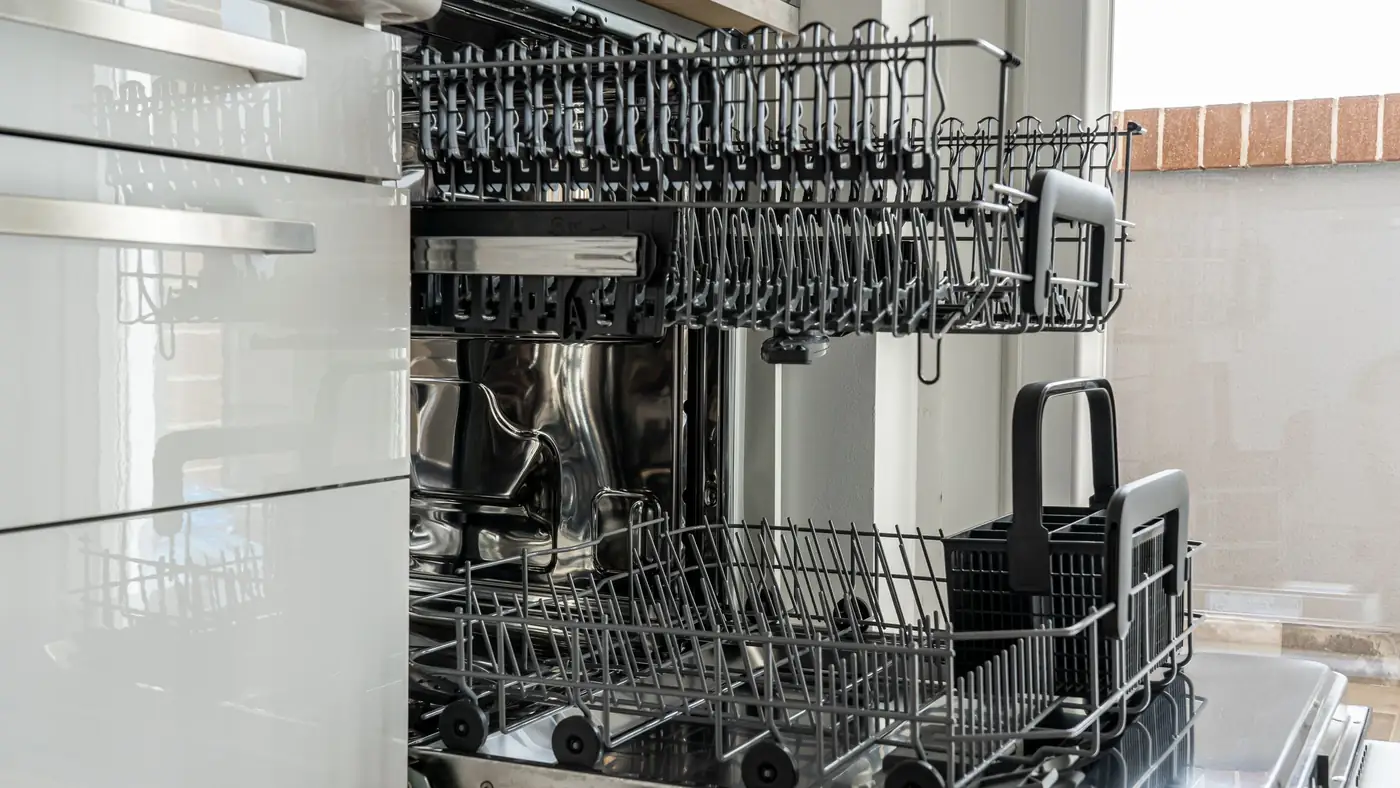 Les deux paniers d'un lave-vaisselle encastré ouverts dans une cuisine, vus de l'intérieur